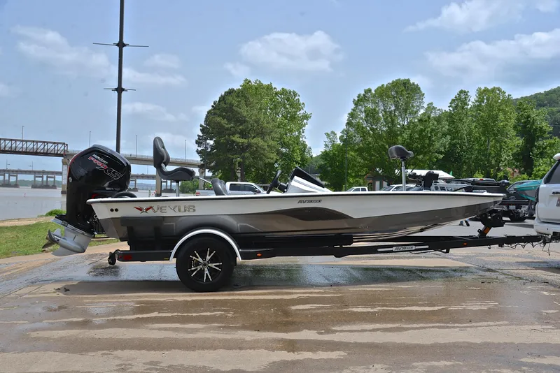Slide: The Image of 2020 Vexus AVX1880 boat on trailer, parked near a river with trees in the background. - 15