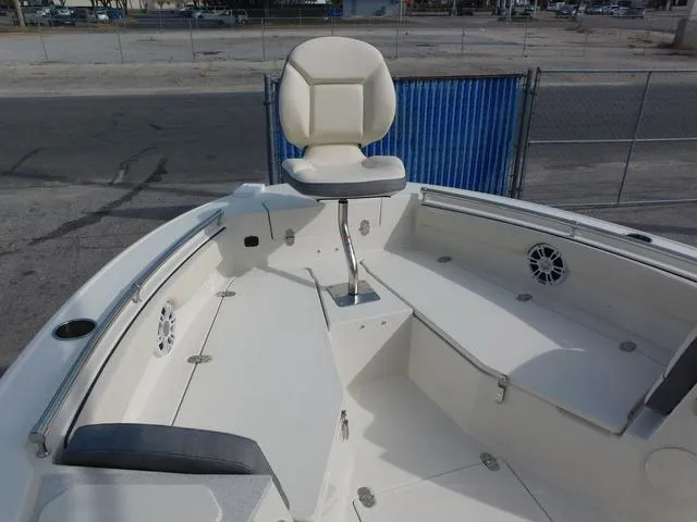 Slide: The Image of 2024 Stingray 216CC boat interior with seating and steering, docked near a fence. - 30