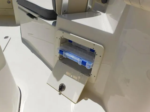 Slide: The Image of 2024 Stingray 253CC boat storage compartment with tackle box, open lid, and seating area. - 22