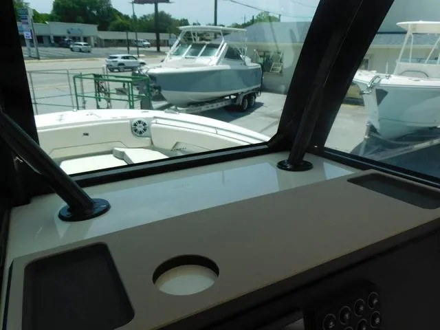 Slide: The Image of 2024 Stingray 253CC boat interior view with docked boats outside. - 29