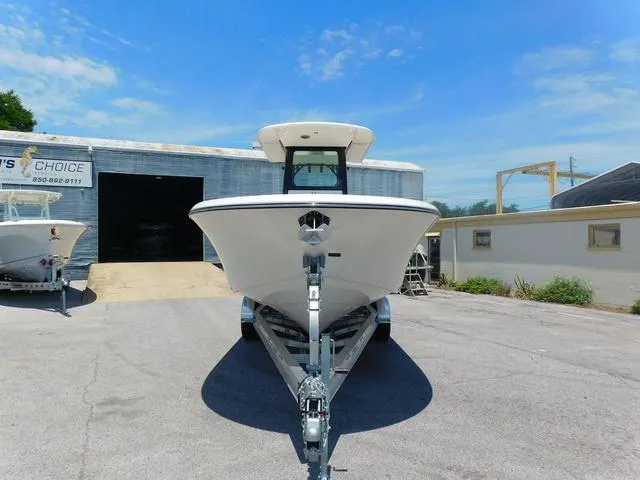 Slide: The Image of 2024 Stingray 253CC boat on trailer, parked outside a warehouse under a clear blue sky. - 6