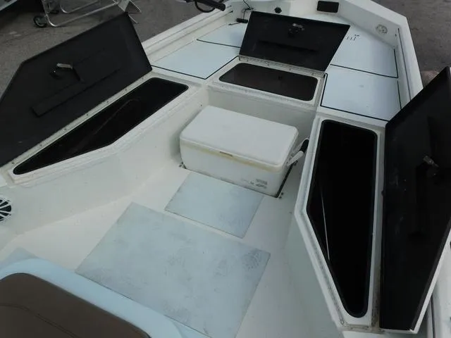 Slide: The Image of 2018 Excel Boats Bay Pro 220 interior with open storage compartments and seating. - 10