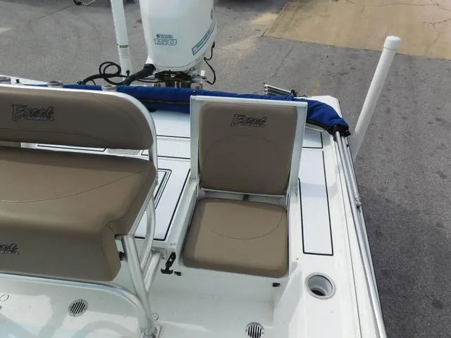Slide: The Image of 2018 Excel Boats Bay Pro 220 with beige seating and motor, docked on pavement. - 17