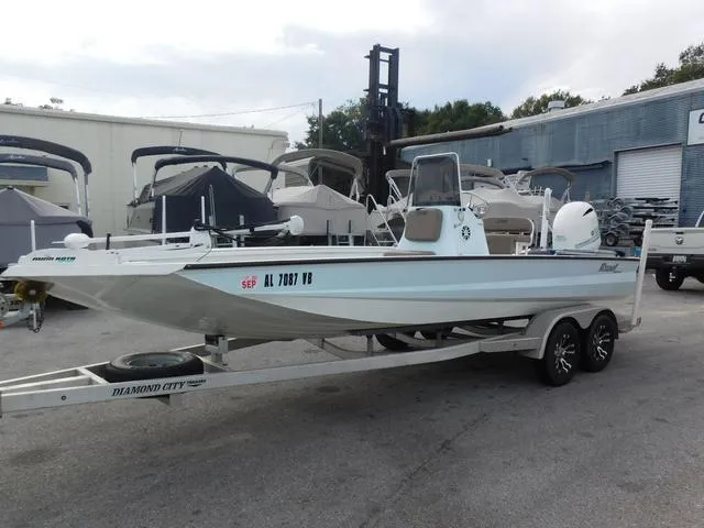 Slide: The Image of 2018 Excel Boats Bay Pro 220 on trailer, parked outdoors near other boats. - 3