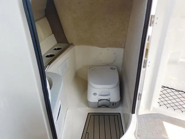 Slide: The Image of 2024 Stingray 231DC boat interior with compact marine toilet and storage space. - 13