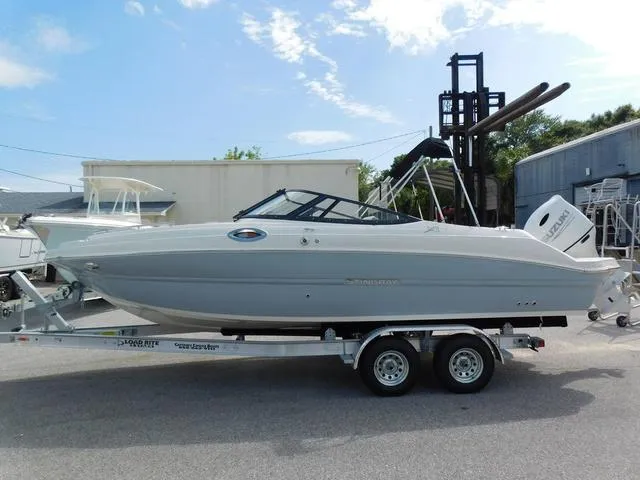Slide: The Image of 2024 Stingray 231DC boat on trailer, parked outdoors under a clear sky. - 3