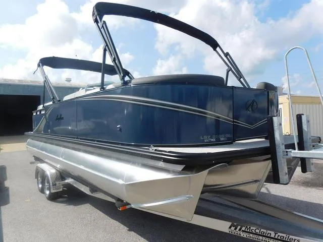 Slide: The Image of 2024 Avalon 2585 LSZ Quad Lounger pontoon boat on trailer, blue exterior, sunny day. - 3