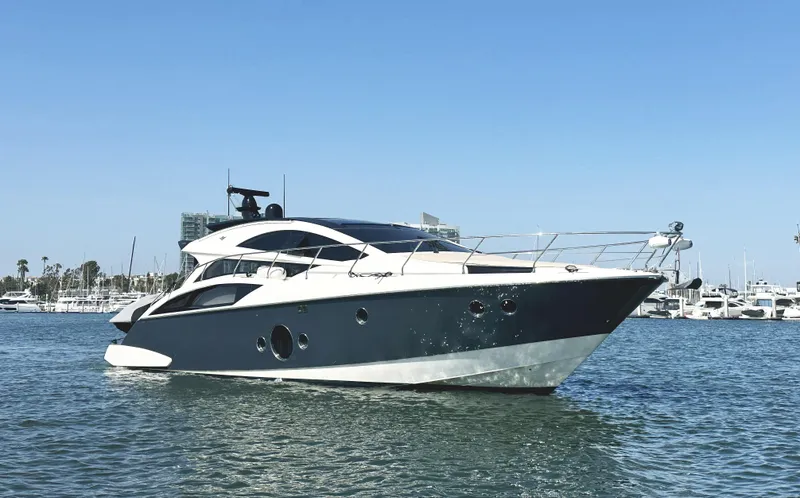 Slide: The Image of 2011 Marquis Sport Coupe yacht on water, clear sky, coastal background. - 1