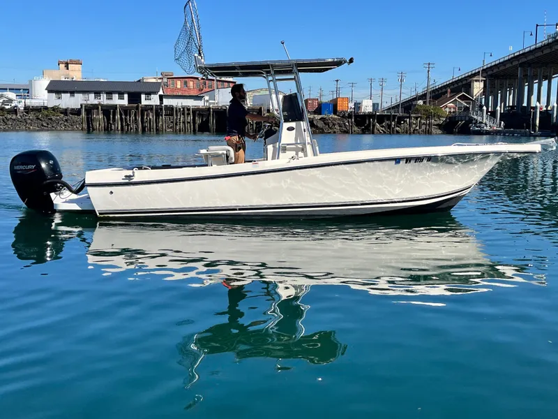 Slide: The Image of 2022 Defiance Commander boat on calm water near a bridge and buildings. - 0
