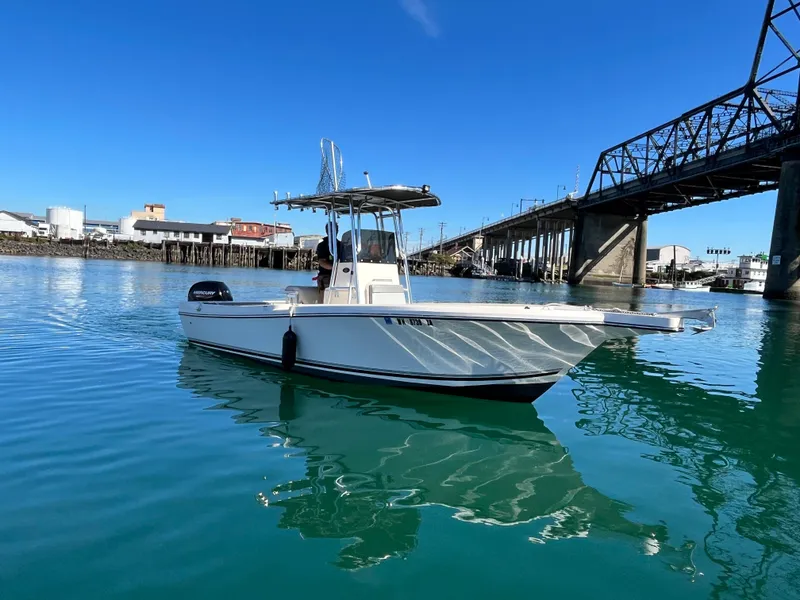 Slide: The Image of 2022 Defiance Commander boat on calm water near a bridge under clear blue sky. - 1
