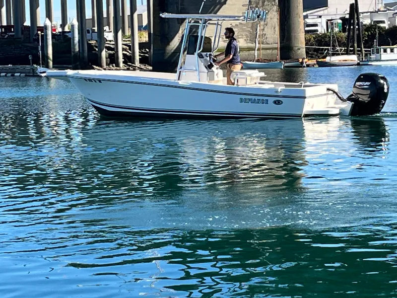 Slide: The Image of 2022 Defiance Commander boat on water, under a bridge, with a person steering. - 16