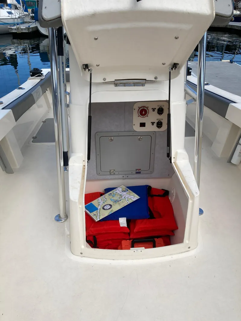 Slide: The Image of Open storage compartment on 2022 Defiance Commander boat with life jackets and a map. - 6