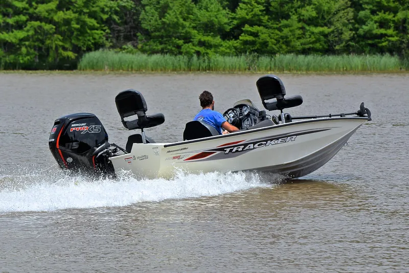 Slide: The Image of 2023 Bass Tracker Pro Team 195 TXE speeding on a lake with lush green trees. - 5