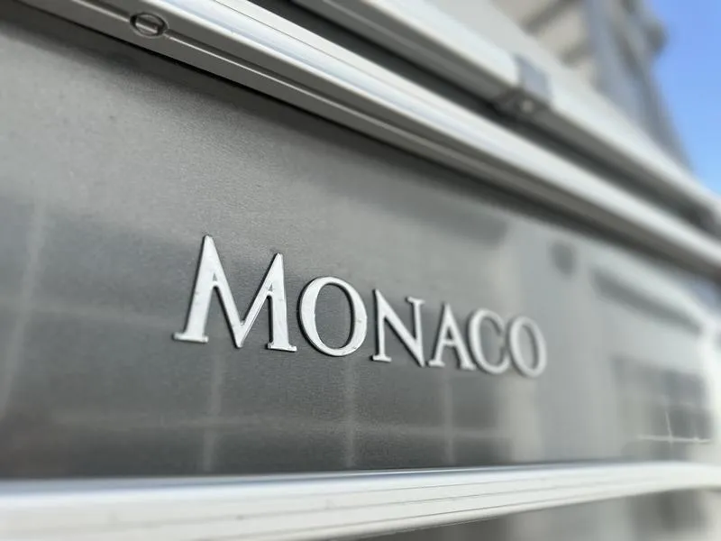 Slide: The Image of 2025 Godfrey Monaco Sundeck 235 SD boat logo on sleek metallic surface. - 16