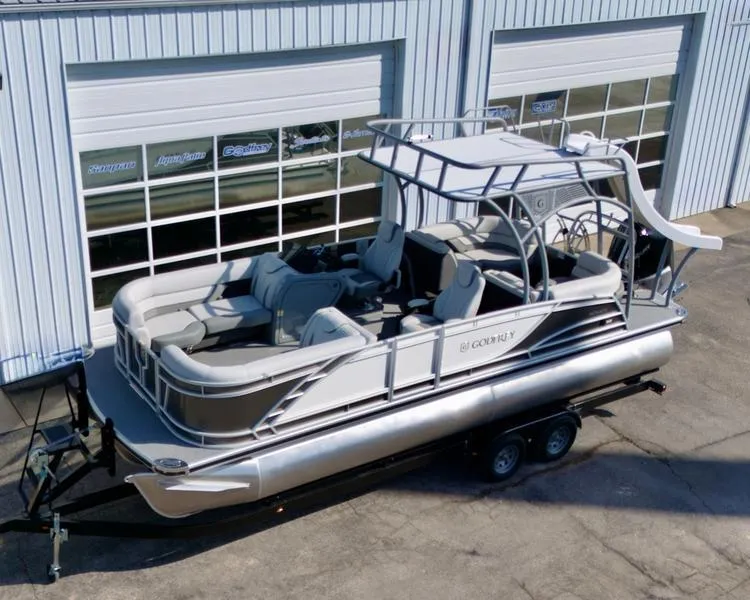 Slide: The Image of 2025 Godfrey Monaco Sundeck 235 SD pontoon boat on trailer, parked outside a garage. - 20