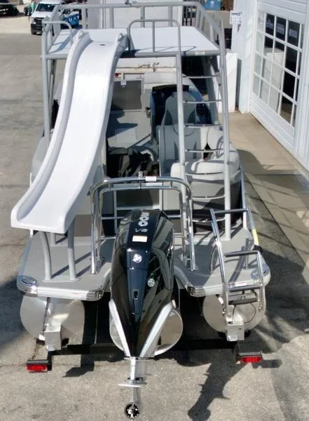 Slide: The Image of 2025 Godfrey Monaco Sundeck 235 SD boat with slide and outboard motor, docked at marina. - 5