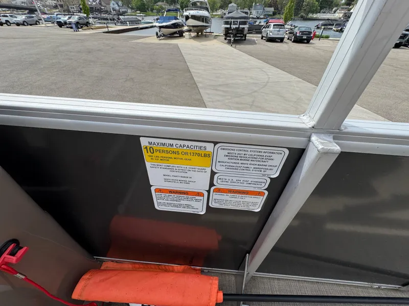 Slide: The Image of 2021 Sun Tracker Party Barge 20 DLX capacity label, docked with vehicles and boats in background. - 9