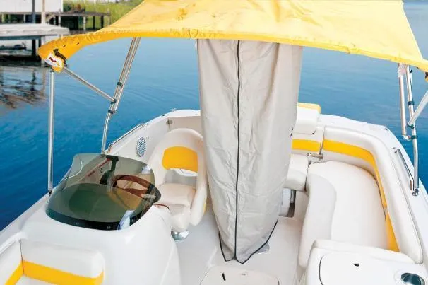 Slide: The Image of 2012 Tahoe 195 boat with yellow canopy and seating, docked on calm water. - 34