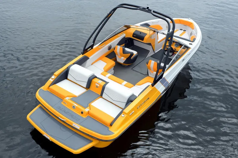 Slide: The Image of 2016 Glastron GTS 207 boat with vibrant orange and white seating on calm water. - 3