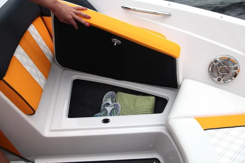 Slide: The Image of 2016 Glastron GTS 207 boat storage compartment with orange and white seating. - 7