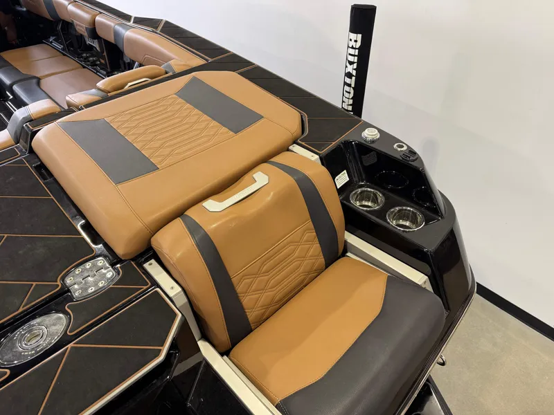 Slide: The Image of 2023 Malibu Wakesetter 26 LSV interior with tan and black seating, cup holders, and sleek design. - 9