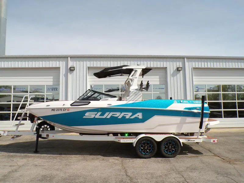 Slide: The Image of 2023 Supra SL 450 boat on trailer, parked outside a building. - 1