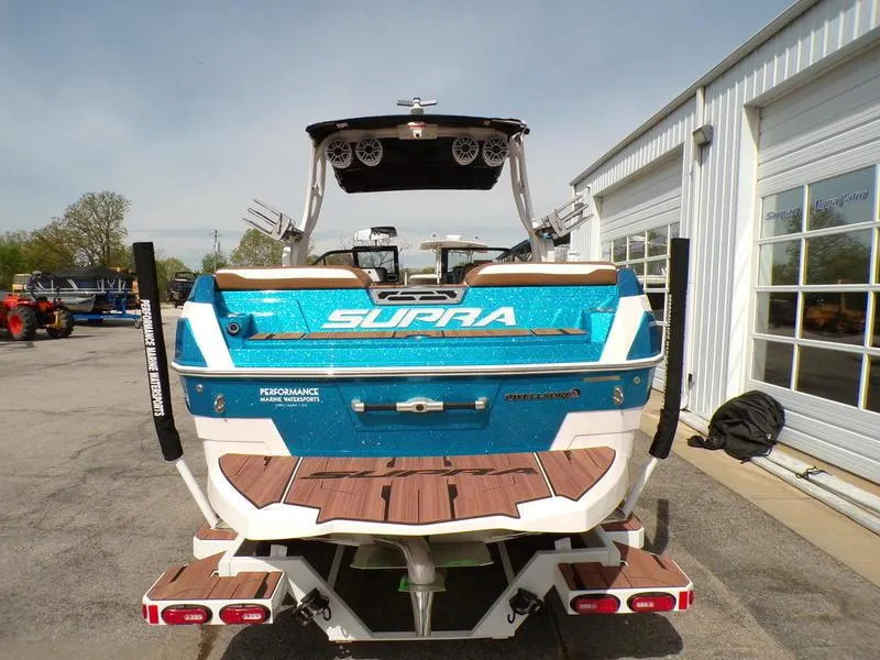 Slide: The Image of 2023 Supra SL 450 boat, blue and white, parked outside a garage. - 12