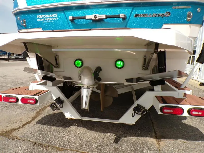 Slide: The Image of Rear view of a 2023 Supra SL 450 boat with green underwater lights. - 2