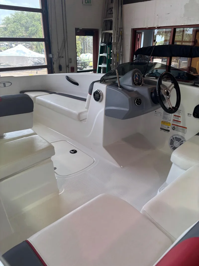 Slide: The Image of 2020 Tracker TAHOE T16 boat interior with seating and steering wheel in a garage setting. - 2