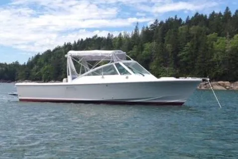 Slide: The Image of 2016 Hunt Yachts Harrier 25 anchored on a serene lake with forested shoreline. - 0