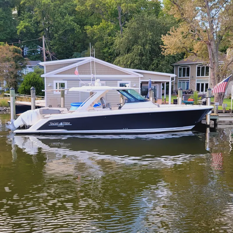 Slide: The Image of 2021 Tiara Yachts 38 LS docked by waterfront homes, reflecting on calm water. - 2