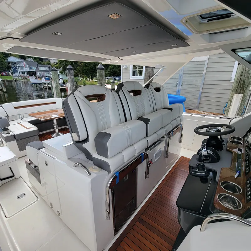 Slide: The Image of 2021 Tiara Yachts 38 LS interior with luxurious seating and modern helm, docked by waterfront homes. - 4