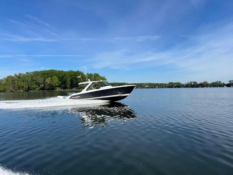 Slide: The Image of 2021 Tiara Yachts 38 LS cruising on a serene lake under a clear blue sky. - 8