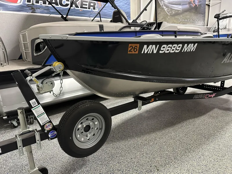 Slide: The Image of 2023 Alumacraft V14 boat on trailer, displayed indoors with visible registration number. - 2