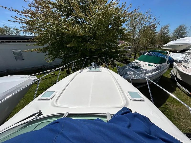 Slide: The Image of 2007 Bayliner 305 boat docked outdoors, surrounded by trees and other boats. - 13
