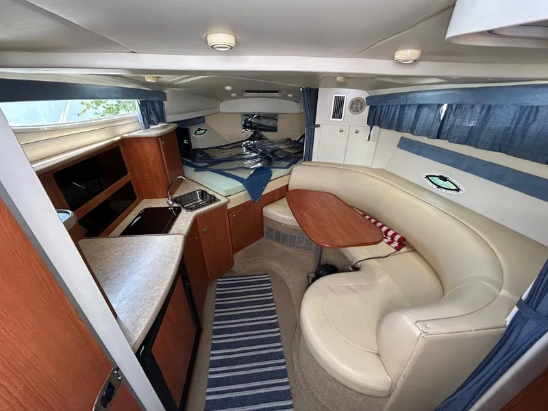 Slide: The Image of 2007 Bayliner 305 cabin interior with kitchenette, seating area, and striped rug. - 20