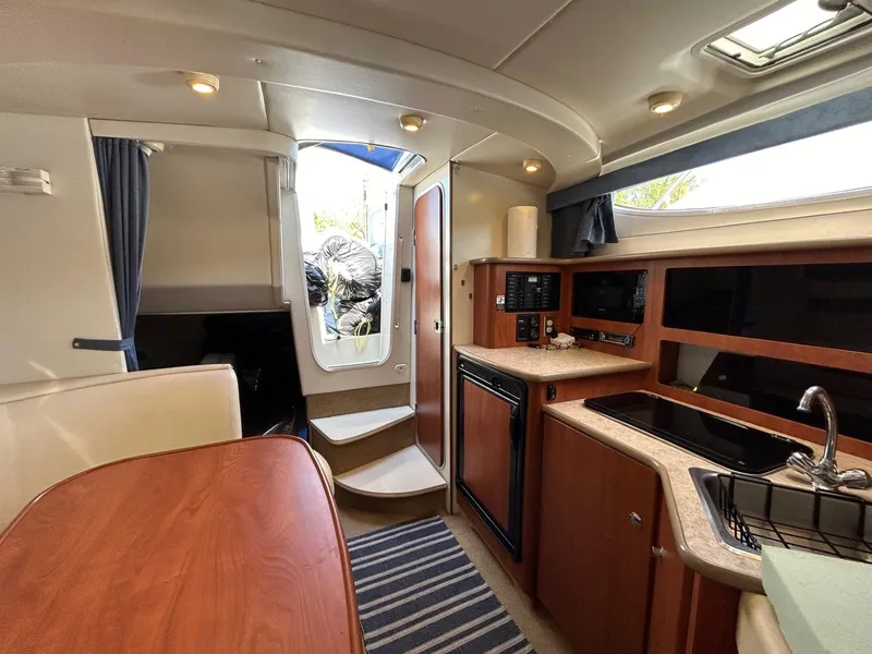 Slide: The Image of 2007 Bayliner 305 interior with kitchenette, dining area, and stairs to deck. - 27