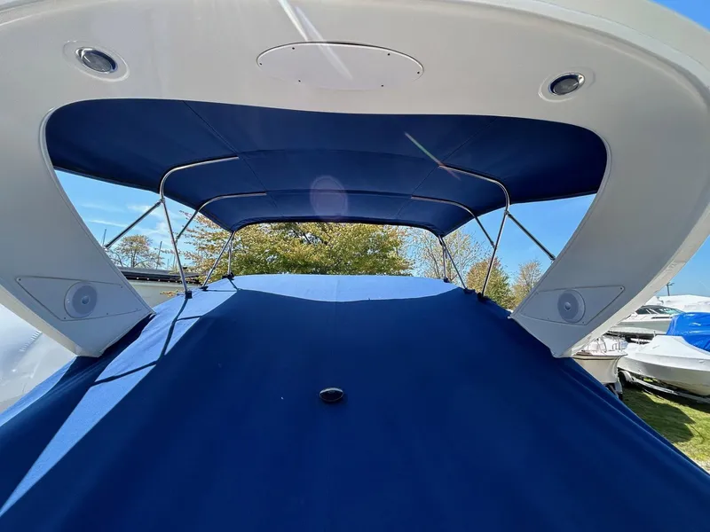 Slide: The Image of 2007 Bayliner 305 boat with blue canopy and cover, docked outdoors. - 6