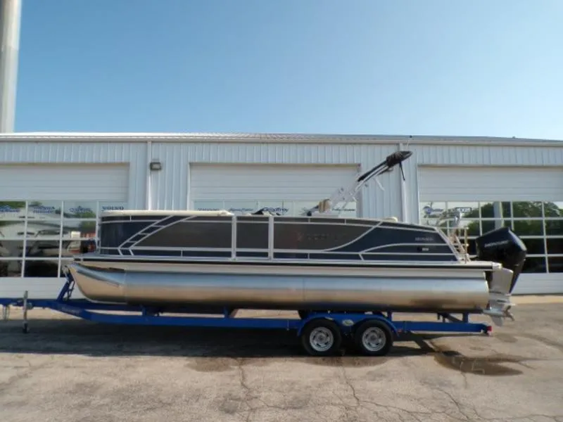 Slide: The Image of 2025 Godfrey Monaco 255 DFL pontoon boat on trailer, parked outside a garage. - 5
