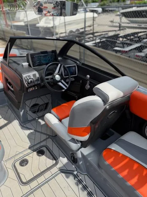 Slide: The Image of 2019 Malibu Wakesetter 22 MXZ interior with orange and gray seating, modern dashboard, and steering wheel. - 13