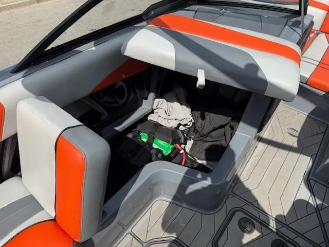 Slide: The Image of 2019 Malibu Wakesetter 22 MXZ interior with orange and gray seating, open storage compartment. - 17