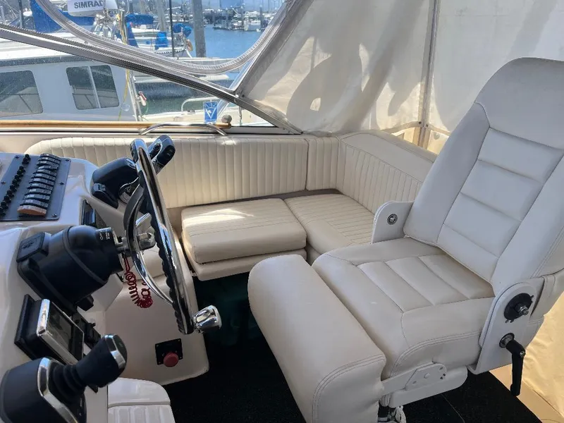 Slide: The Image of 2003 Grady-White 33 Express helm with white seating and steering wheel, docked at marina. - 17