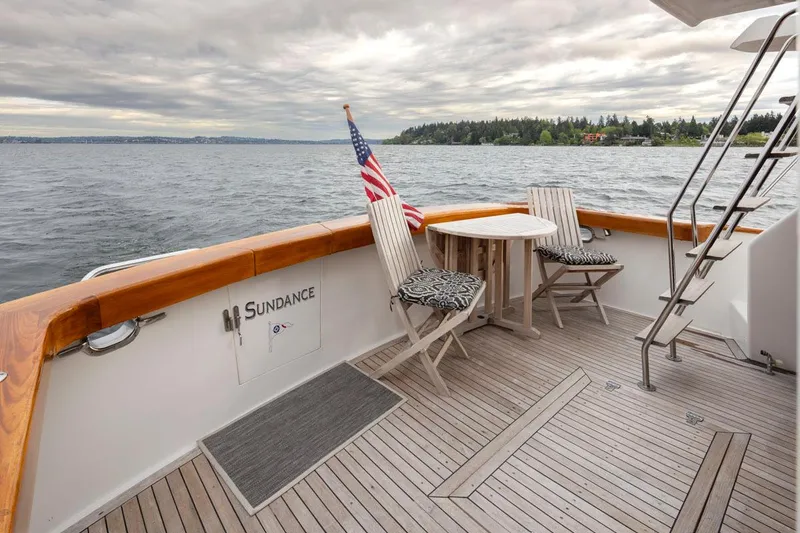 Slide: The Image of 1989 Ocean Alexander 50 Sedan yacht deck with seating, table, and American flag on a calm lake. - 29