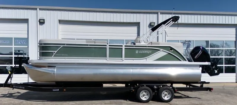 Slide: The Image of 2025 Godfrey SWEETWATER 2286 SB pontoon boat on trailer, parked outside a garage. - 4