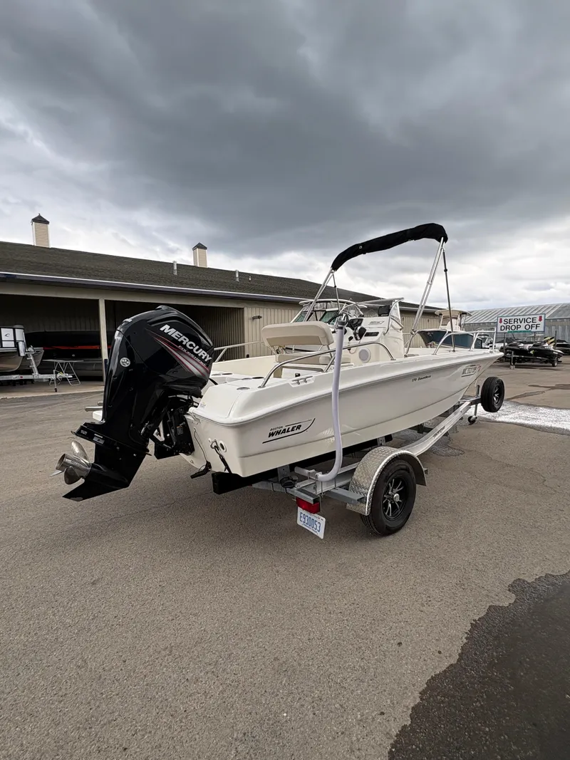 Slide: The Image of 2019 Boston Whaler 170 Dauntless boat on trailer under cloudy sky. - 2