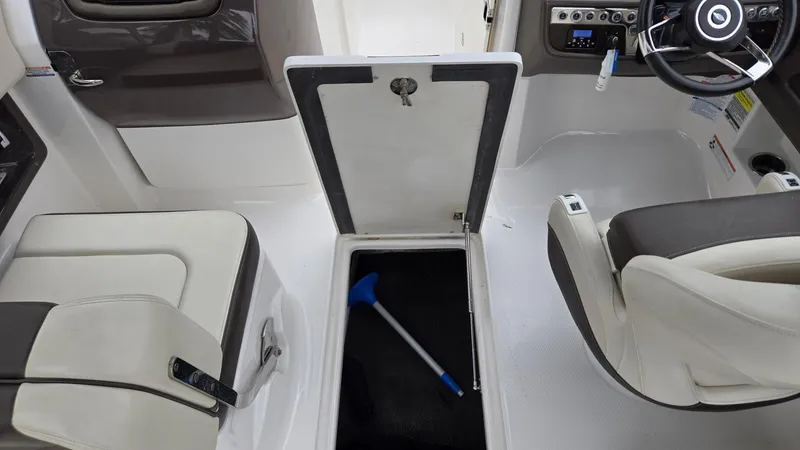 Slide: The Image of 2021 Chaparral 230 boat interior with open storage compartment and steering wheel. - 13