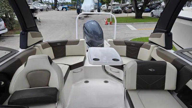 Slide: The Image of 2021 Chaparral 230 boat interior with seating and table, parked at a marina. - 5