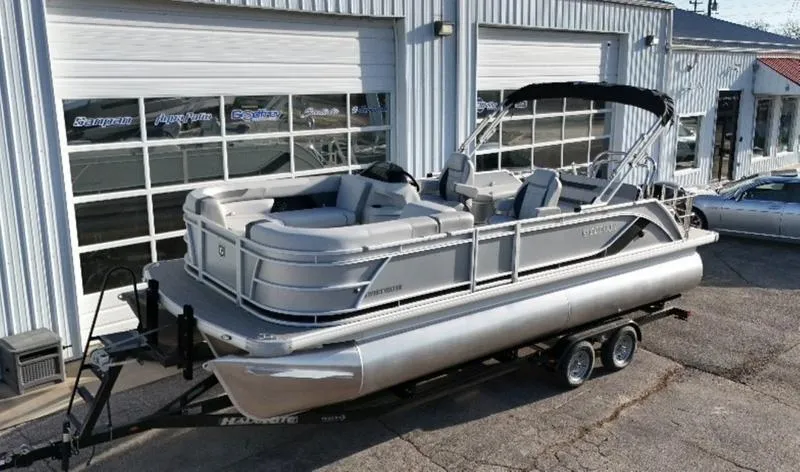Slide: The Image of 2025 Godfrey Sweetwater 2286 SFLC pontoon boat on trailer, parked outside a garage. - 5