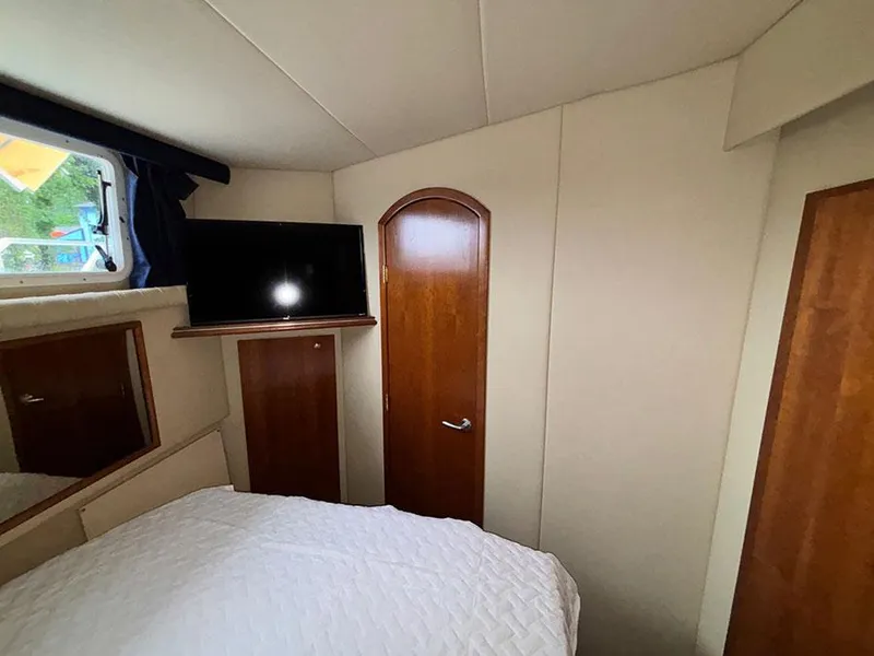 Slide: The Image of 2004 Cruisers Yachts 375 Motoryacht bedroom with TV, wooden door, and window. - 18