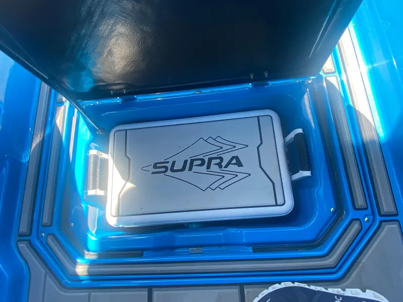 Slide: The Image of 2021 Supra SL 450 storage compartment with logo, blue interior. - 23
